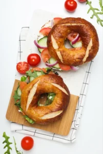 Assorted freshly baked bagels with various toppings and fillings on a wooden board, highlighting the diversity and appeal of bagels worldwide