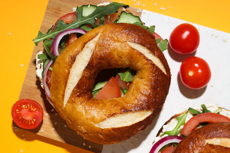 Assorted freshly baked bagels with various toppings and fillings on a wooden board, highlighting the diversity and appeal of bagels worldwide