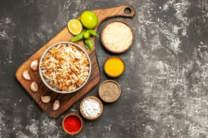 Assorted fresh ingredients for chicken fried rice including chicken, jasmine rice, peas, carrots, and soy sauce on a kitchen counter.