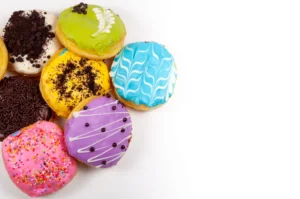 Assorted gourmet super donuts with vibrant toppings and unique flavors displayed on a wooden table, showcasing varieties from classic sugar-glazed to exotic matcha and bacon-infused creations.