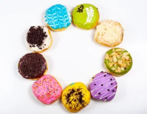 Assorted gourmet super donuts with vibrant toppings and unique flavors displayed on a wooden table, showcasing varieties from classic sugar-glazed to exotic matcha and bacon-infused creations.