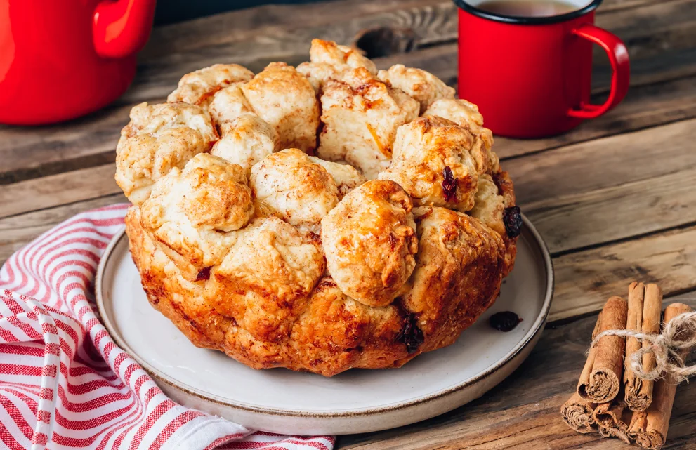 A plate of warm monkey bread with pieces being pulled apart, showcasing the soft, fluffy interior.