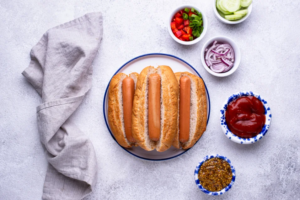 Delicious air fryer hot dogs with a golden, crispy exterior and juicy interior, served with a side of toasted buns and a variety of toppings.