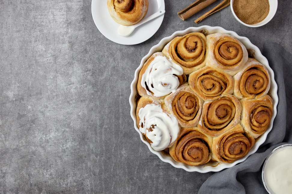 Freshly baked cinnamon rolls with gooey frosting on a cooling rack