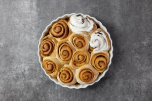 Freshly baked cinnamon rolls with gooey frosting on a cooling rack