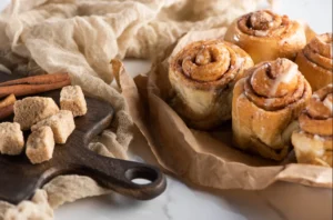 Freshly baked cinnamon rolls in a pan with heavy cream poured at the bottom, showcasing their golden-brown crust and moist, fluffy texture.