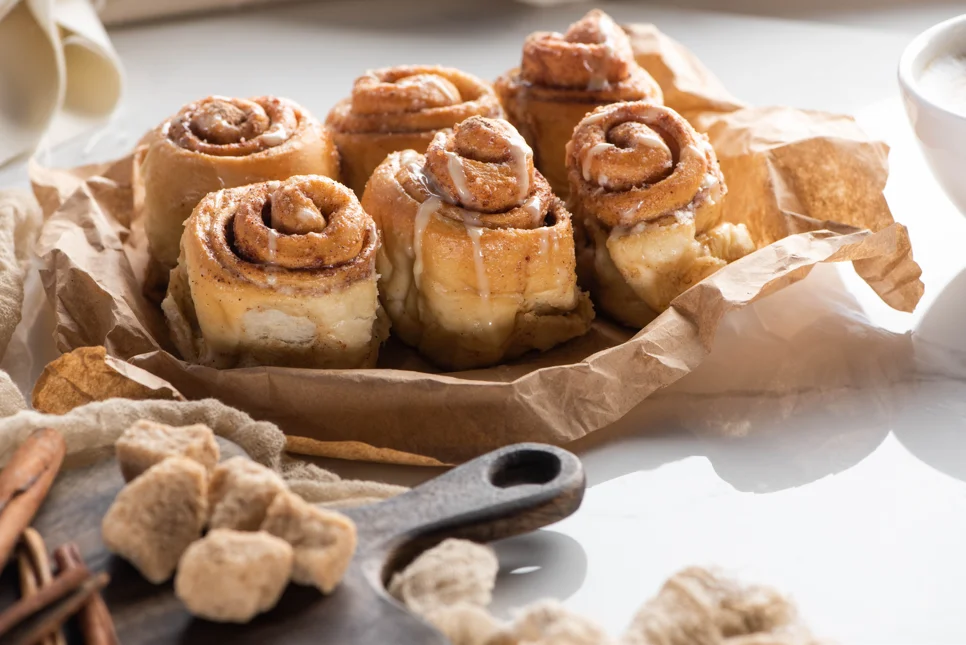 Freshly baked cinnamon rolls in a pan with heavy cream poured at the bottom, showcasing their golden-brown crust and moist, fluffy texture.