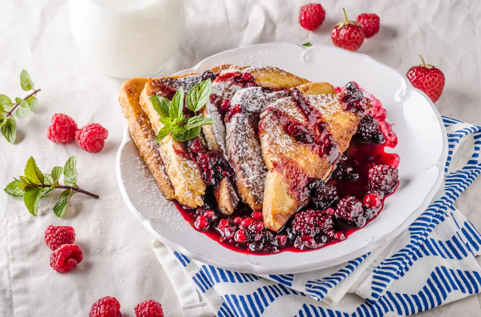 Delicious dairy-free French toast served with fresh berries and maple syrup on a rustic wooden table, showcasing a milk-free breakfast option.