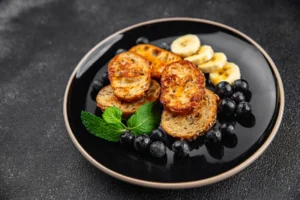 Golden brown French toast on a plate with maple syrup drizzle and fresh berries