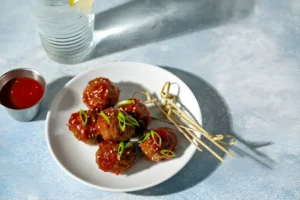 Delicious sweet and sour meatballs served in a tangy sauce with a sprinkle of sesame seeds and green onions.